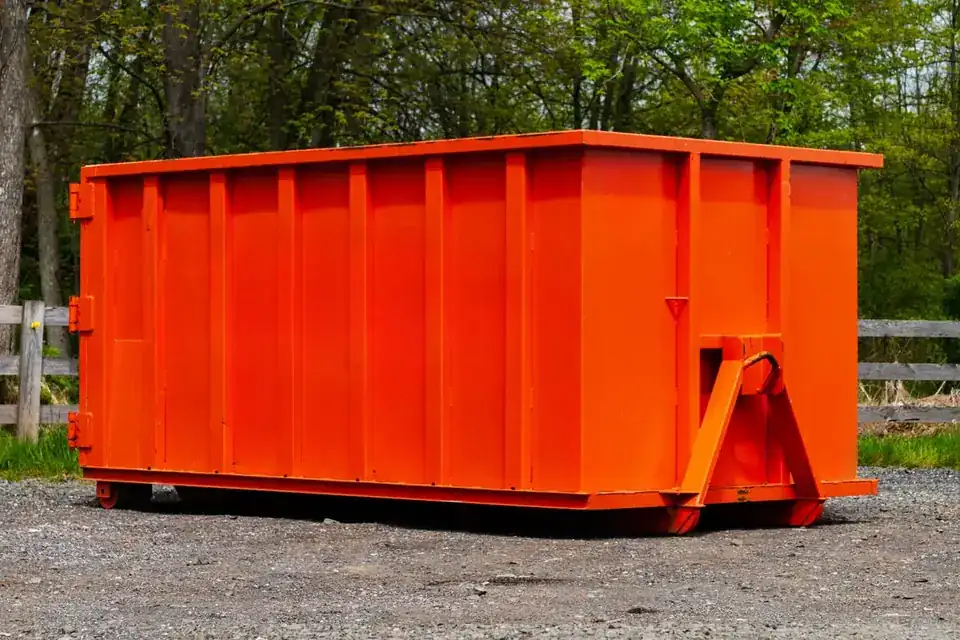 Orange 15-yard style roll-off dumpster on gravel