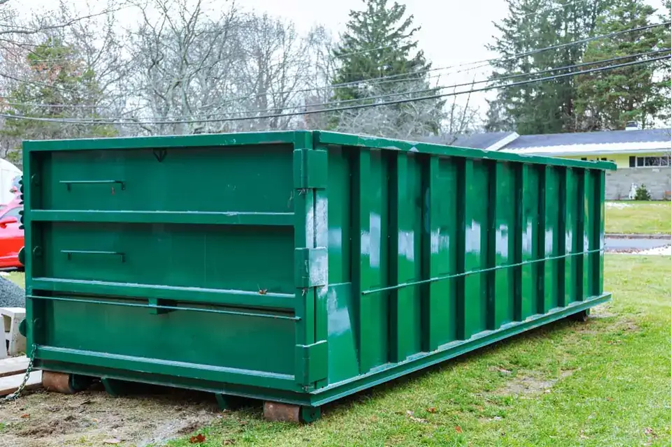Green roll-off dumpster on timbers for a backyard project